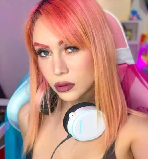 Close-up shot of YouTube creator Mandy Candy posing with headphones around her neck with a colorful background.