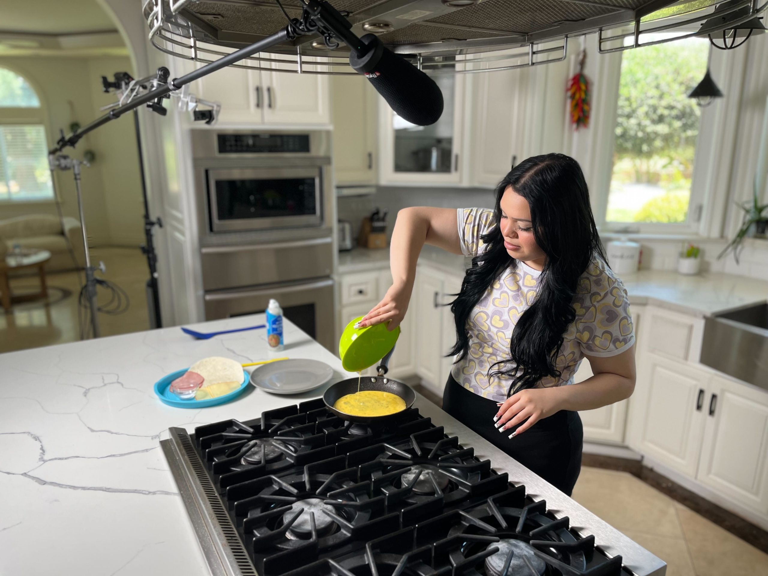 Multi-platform video creator Karina Garcia in a kitchen cooking on the stove top with microphone leaning in front