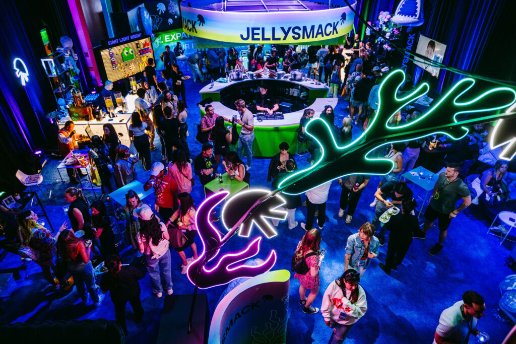 Overhead view of crowded party held in a large ballroom with neon lights.